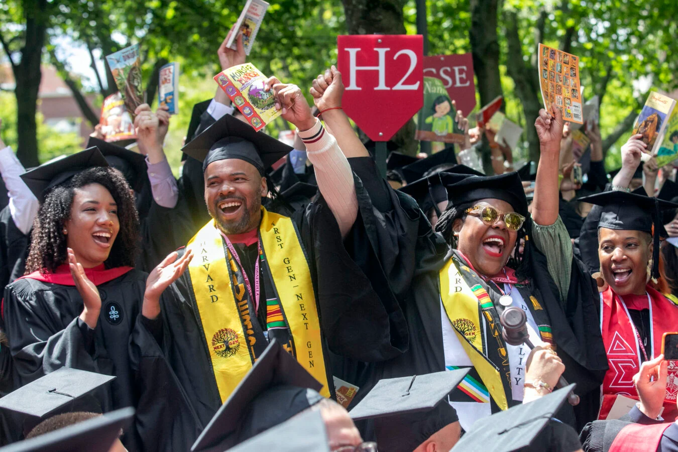 Harvard Graduate School of Education graduates hold up children’s books. Photo: Jon Chase